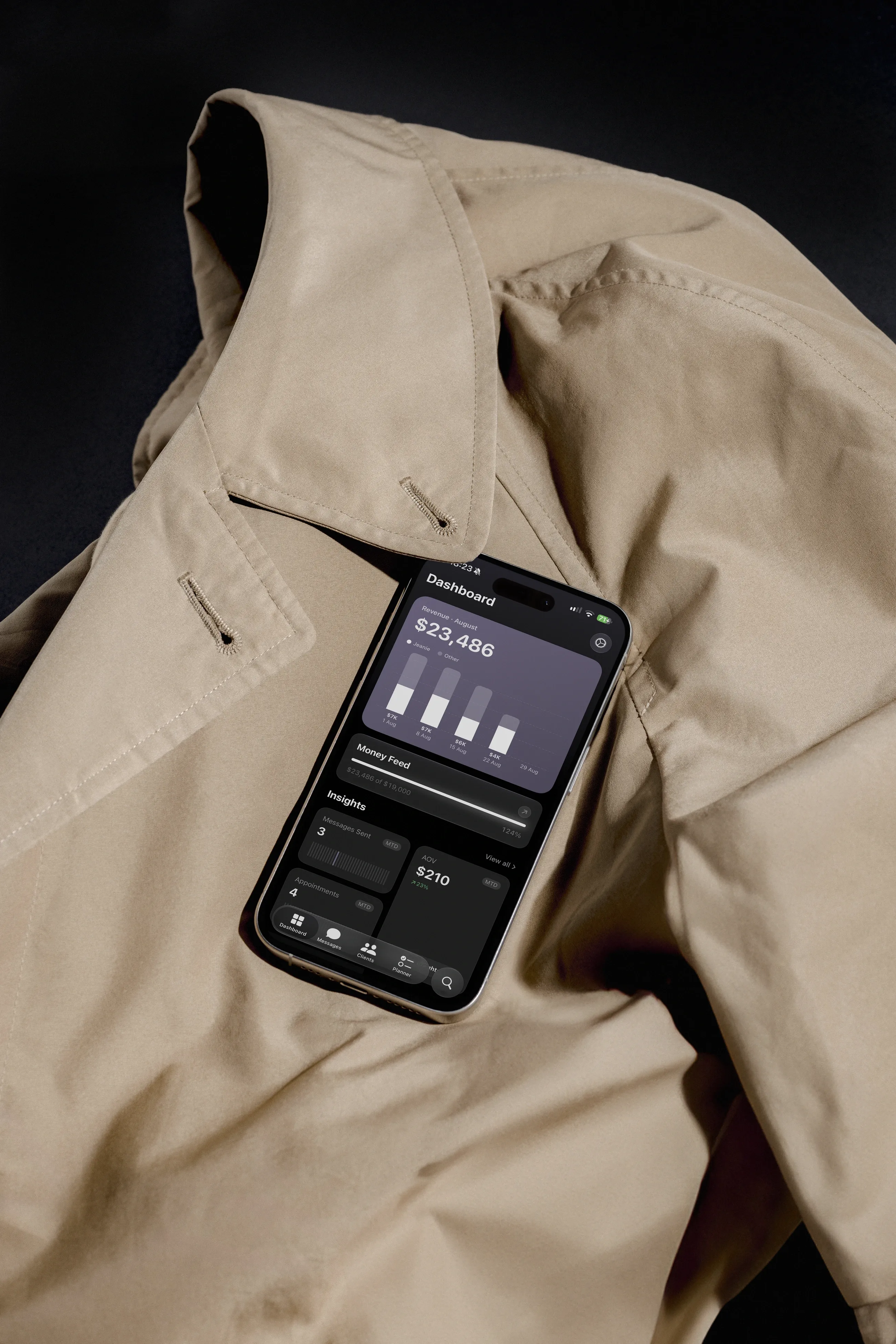 Jeanie's Dashboard open on an iPhone, resting on a trench coat